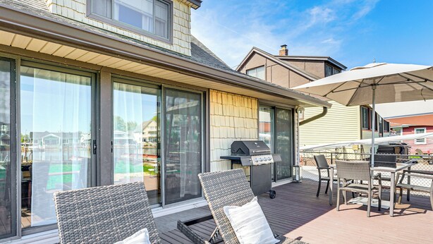 A deck with wicker lounge chairs and a grill area. - 4 Boat Slips: Getaway on Mouth of Clinton River! (Harrison)