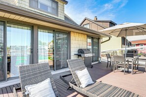 Une terrasse dotée de fauteuils de jardin en osier et d’un espace barbecue.