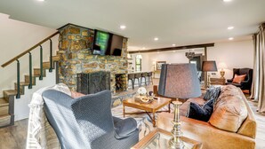 Un salon avec une cheminée en pierre, un canapé, une table basse et un téléviseur fixé au mur.
