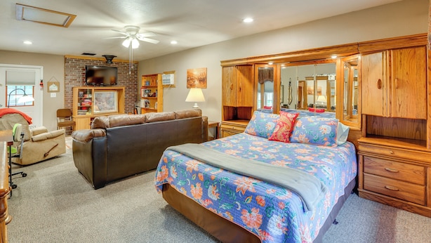 A bedroom with a large bed, a sofa, a wooden wardrobe, and a ceiling fan. - Walk to Dtwn: Ironton Home in Historic District (Ironton)