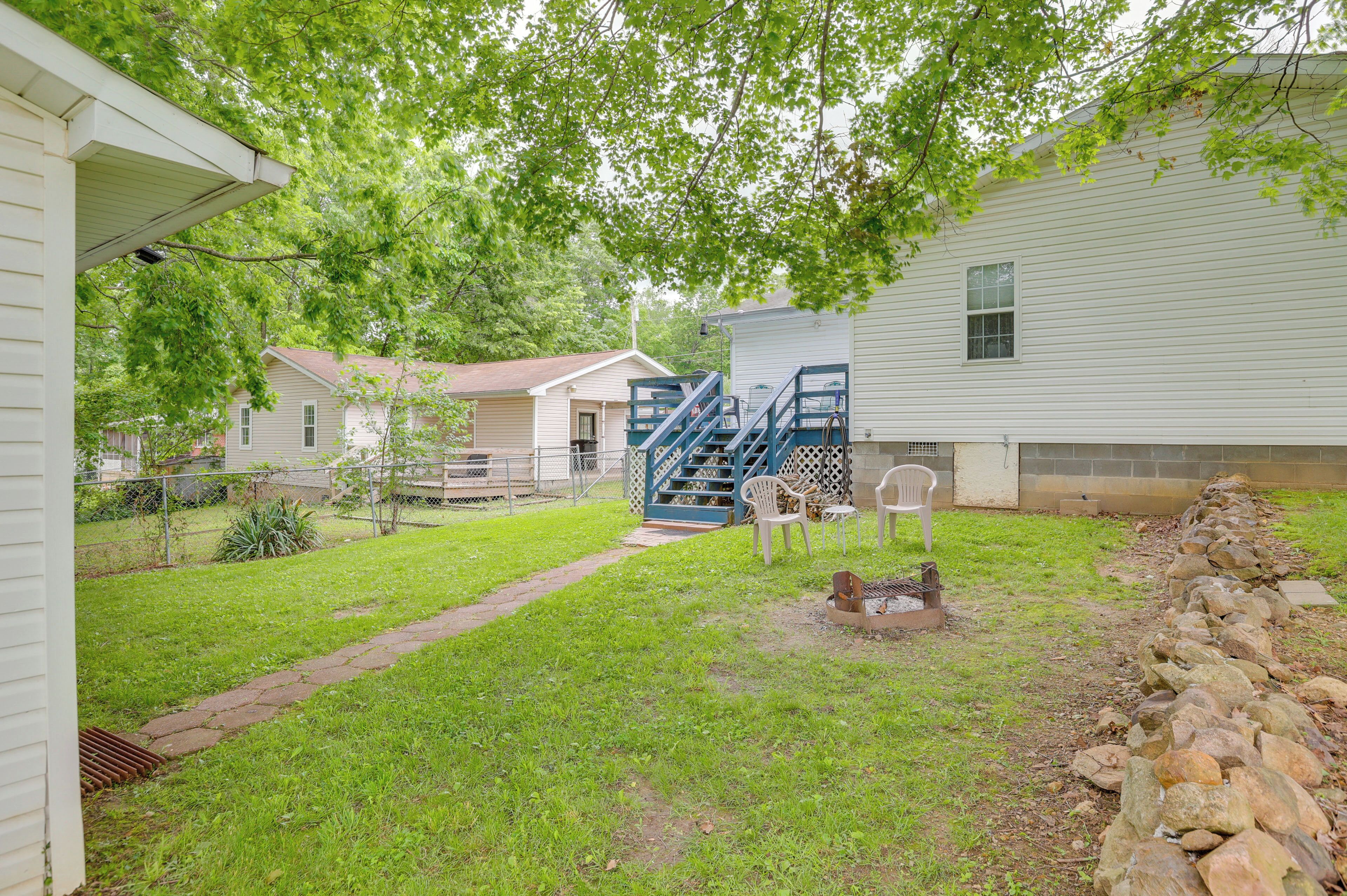 A residential backyard with a grassy lawn, a stone wall, and a blue staircase leading to a garage.