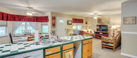 A spacious living area with a kitchen island, dining table, and a television.