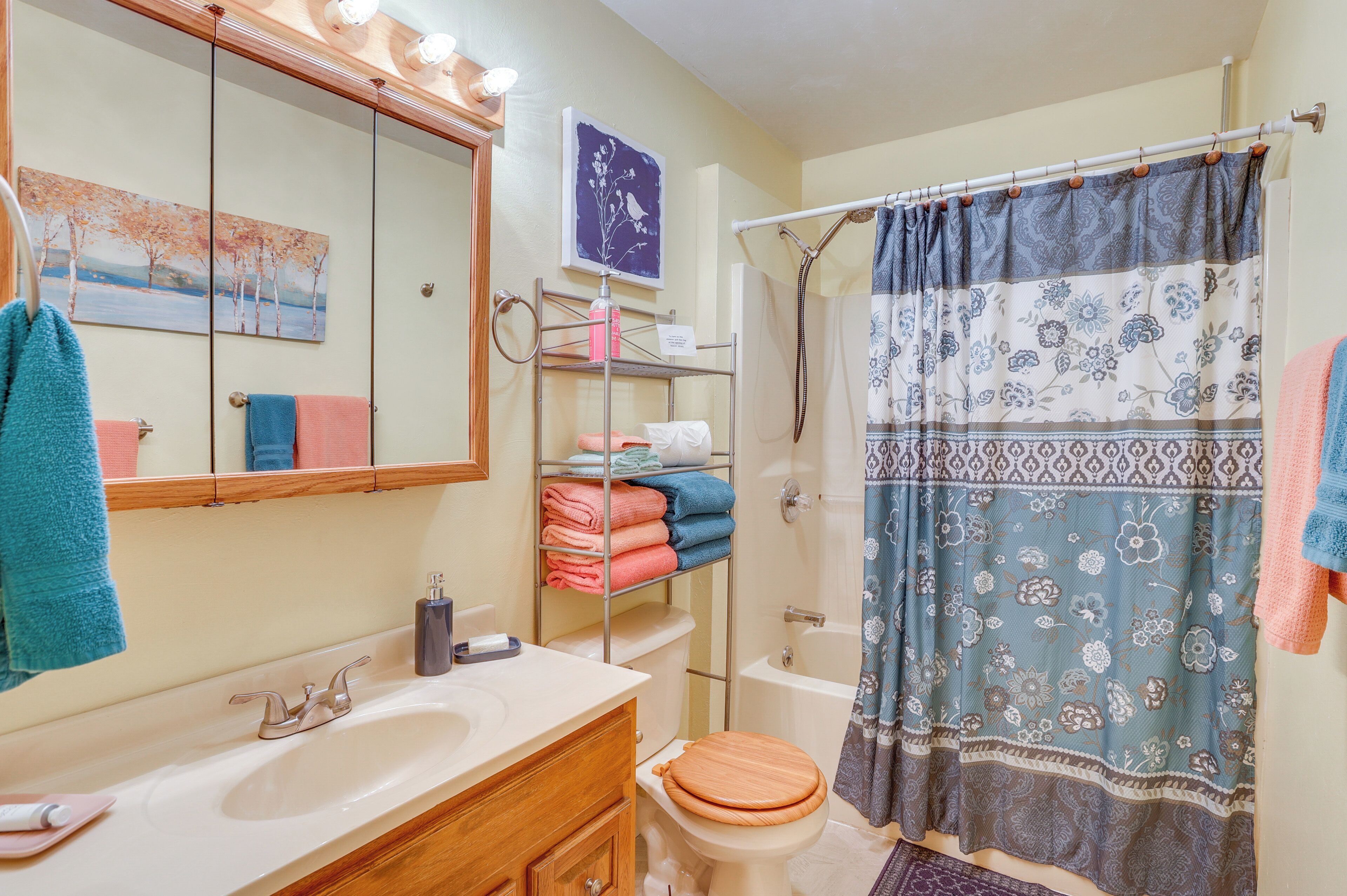 Une salle de bain équipée d’un lavabo, d’un miroir, de toilettes et d’un rideau de douche.