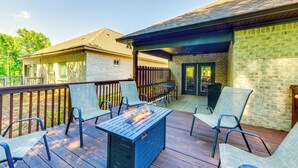 Eine Terrasse im Freien mit Feuerstelle, Sitzgelegenheiten und einem überdachten Bereich.