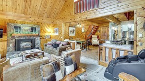 Ein gemütliches Blockhaus-Interieur mit Kamin, bequemen Sitzgelegenheiten, einem Essbereich und einer Küche.