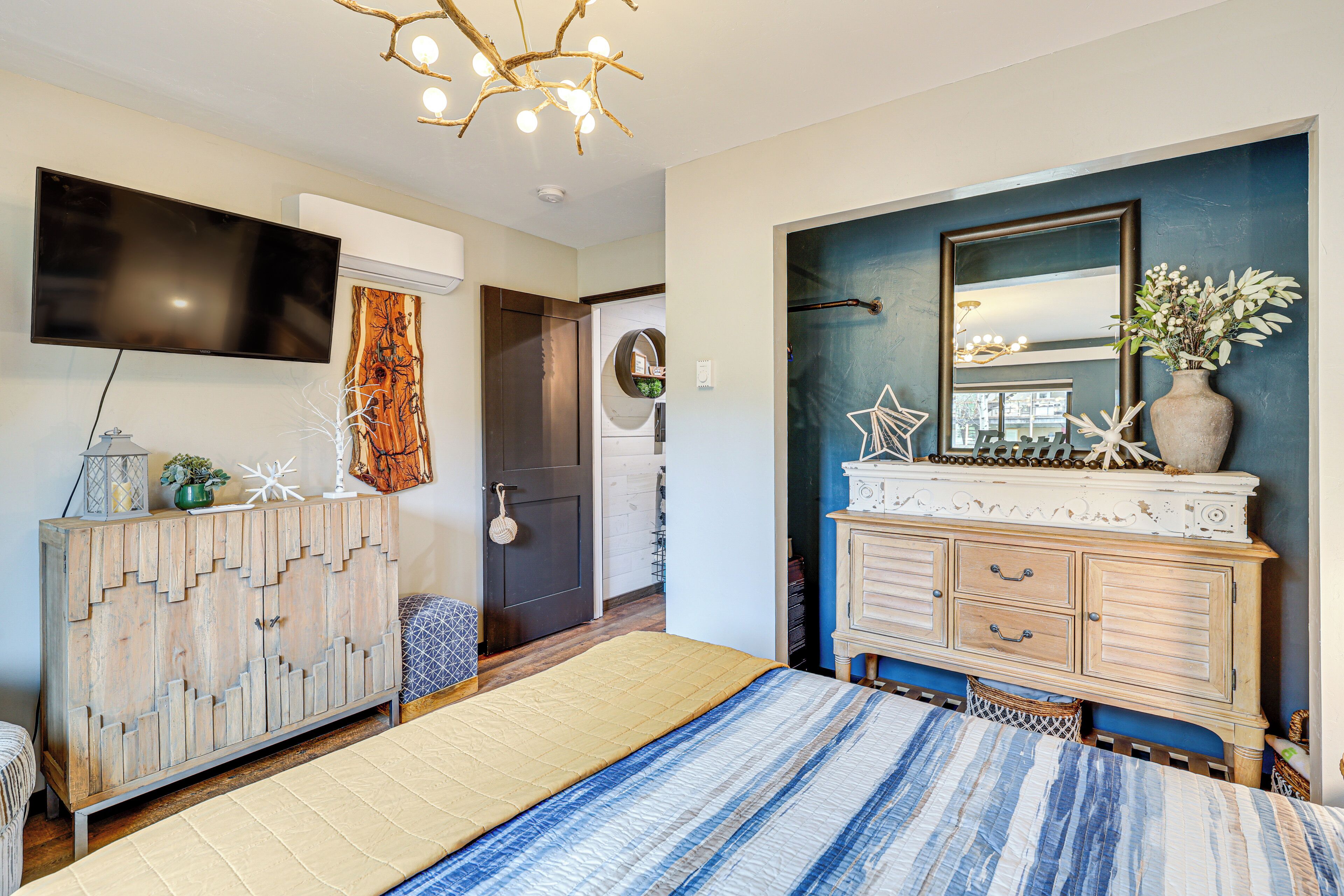 A bedroom with a bed, a dresser, a television, and a mirror.