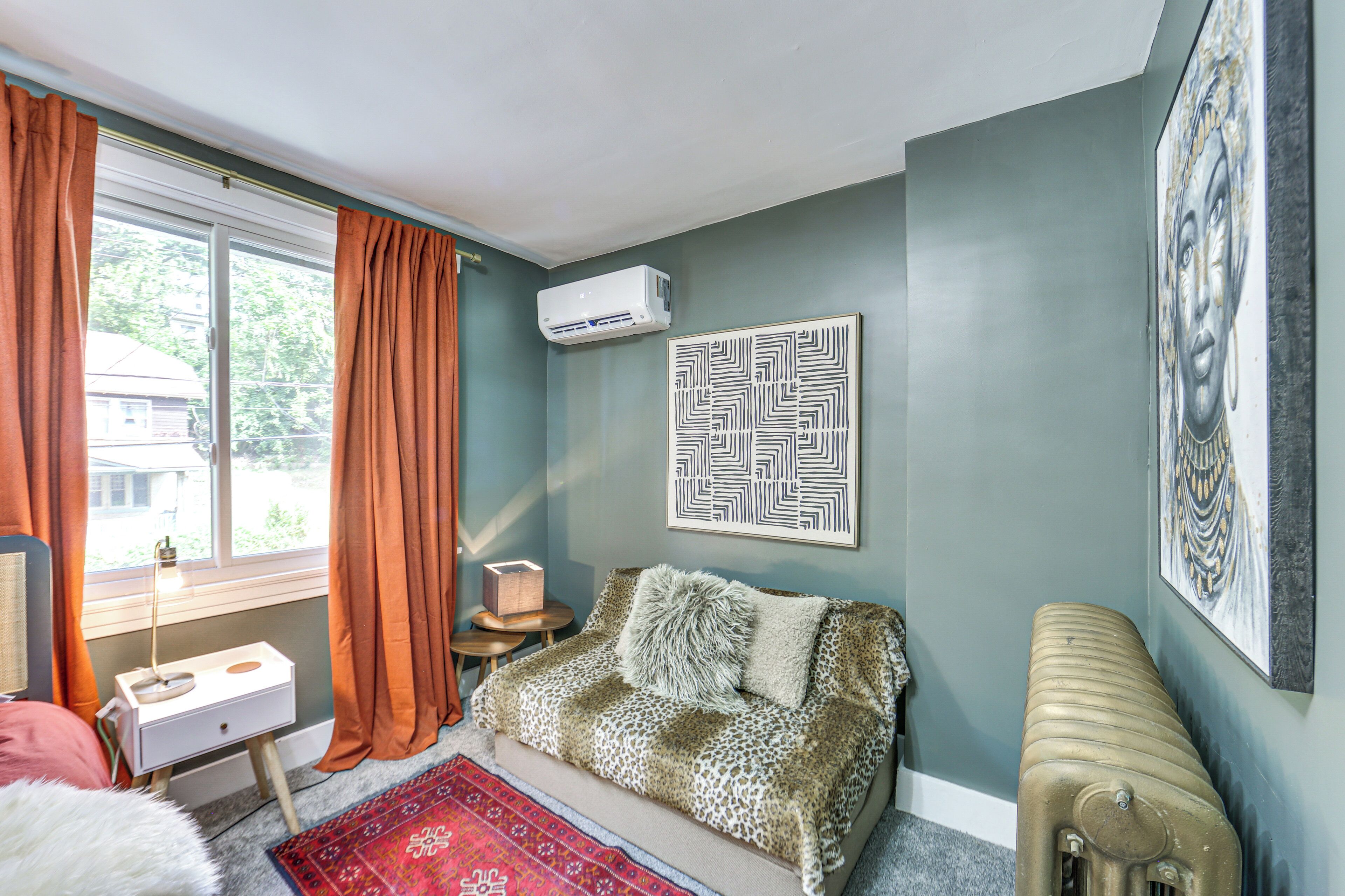 A room with a sofa, a small table, a radiator, and a window with curtains.
