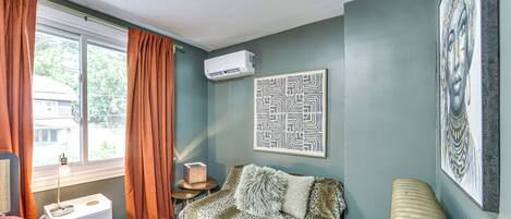 A room with a sofa, a small table, a radiator, and a window with curtains.