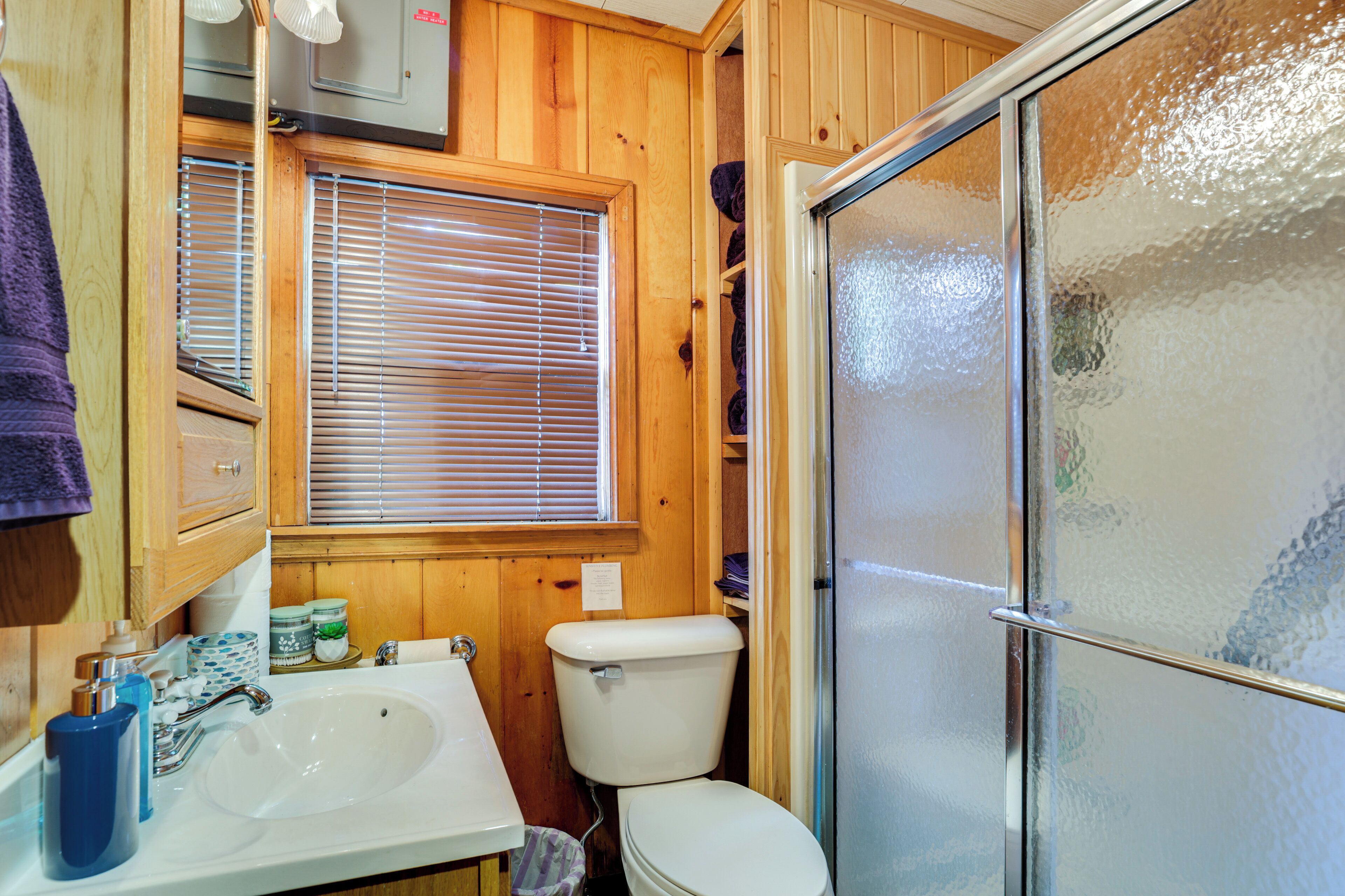 A compact bathroom with a sink, toilet, and frosted glass shower door.
