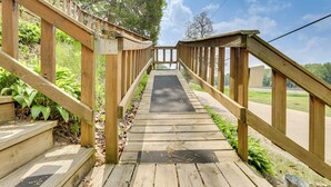 A wooden staircase leading to a deck with railings, surrounded by greenery. - Walk to Wyalusing Beach: Cabin w/ River View! (Bagley)