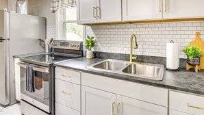 Una cocina moderna con gabinetes blancos, electrodomésticos de acero inoxidable y encimera negra.