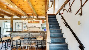 A wooden interior with a staircase, rustic decor, and a bar area. - True North Farm House - Historic Family Home (Irasburg)