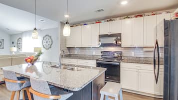 A modern kitchen with a granite countertop, stainless steel appliances, and white cabinetry.