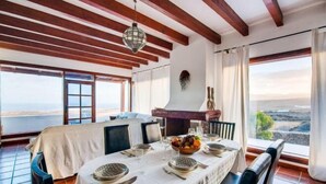 A dining area with a table set for four, large windows, and a view of the sea. - Villa Vista Mar (Tias)