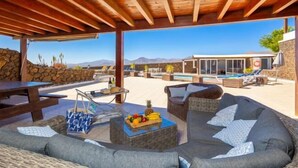 An outdoor patio area with wicker furniture, a wooden table, and a fruit basket. - Villa Vista Mar (Tias)