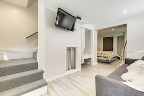 A bedroom with a bed, a TV mounted on the wall, a staircase, and a sofa. - 3 Mi to Mashpee Commons: Family Home w/ Fireplace (Mashpee)