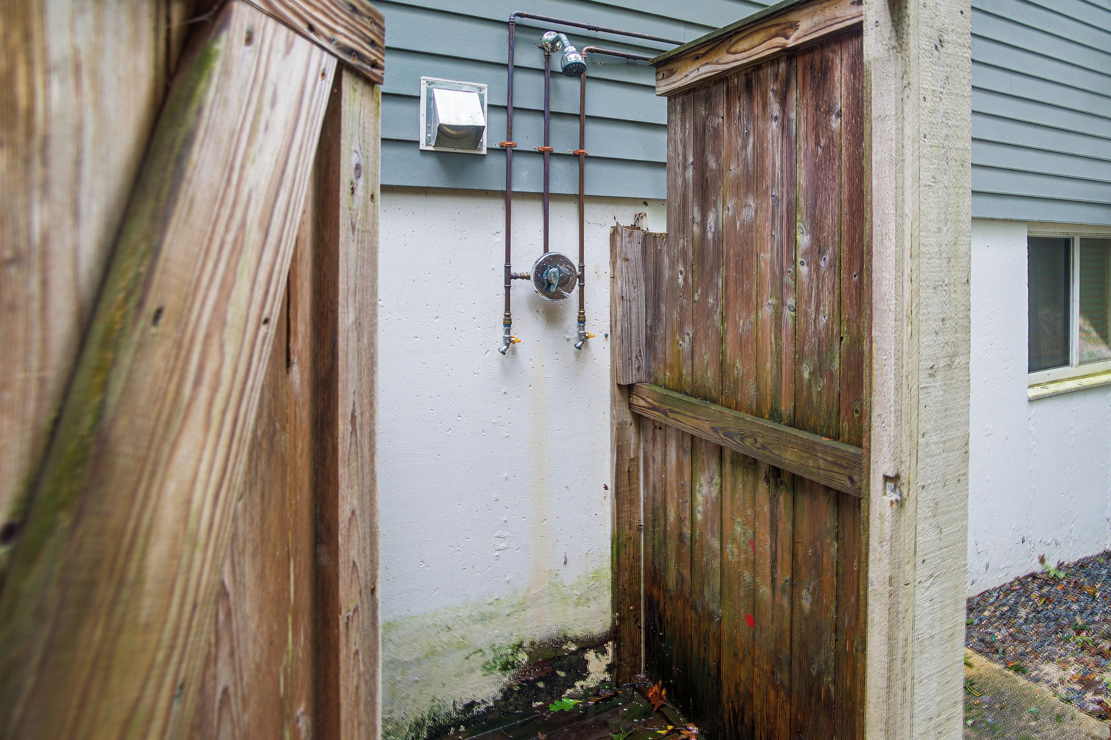 A wooden gate with a metal latch, a small window, and a metal pipe running along the wall.