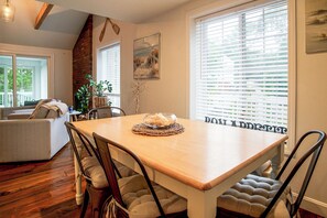 Un comedor con una mesa de madera, sillas acolchadas y un cuenco de pan.