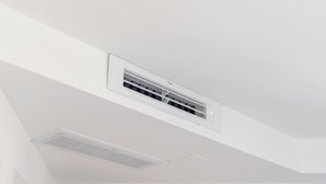 Un plafond blanc avec un appareil de climatisation central et un luminaire encastré.