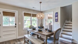 A dining area with a wooden table set for four, a bench, and a hanging light fixture.