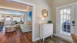 A spacious living room with a white sofa, a round coffee table, and a white console table with a mirror.
