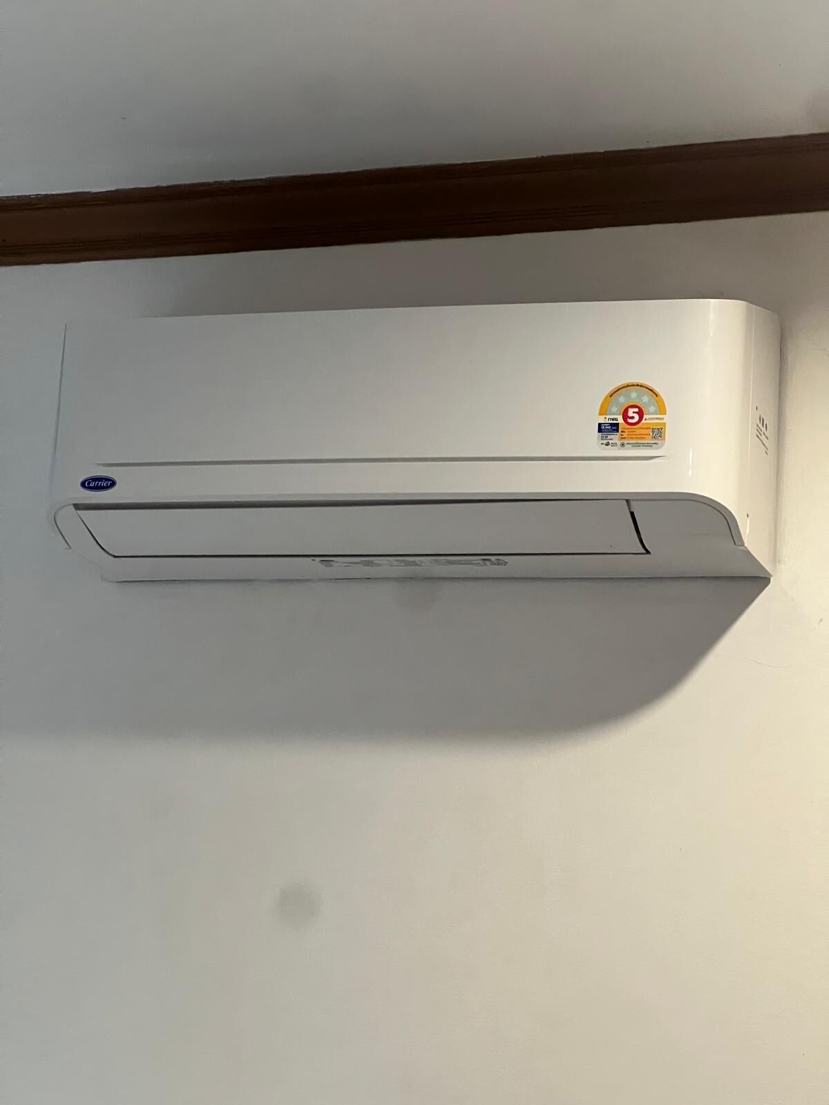 A white wall-mounted air conditioner with a Carrier logo, a 5-star energy efficiency rating sticker, and a small control panel.