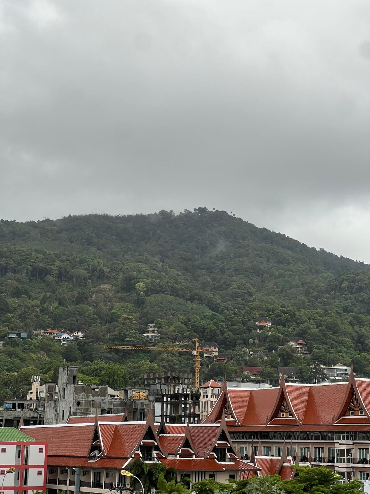 Um edifício tradicional com telhado vermelho e vários níveis, rodeado por colinas verdes exuberantes.