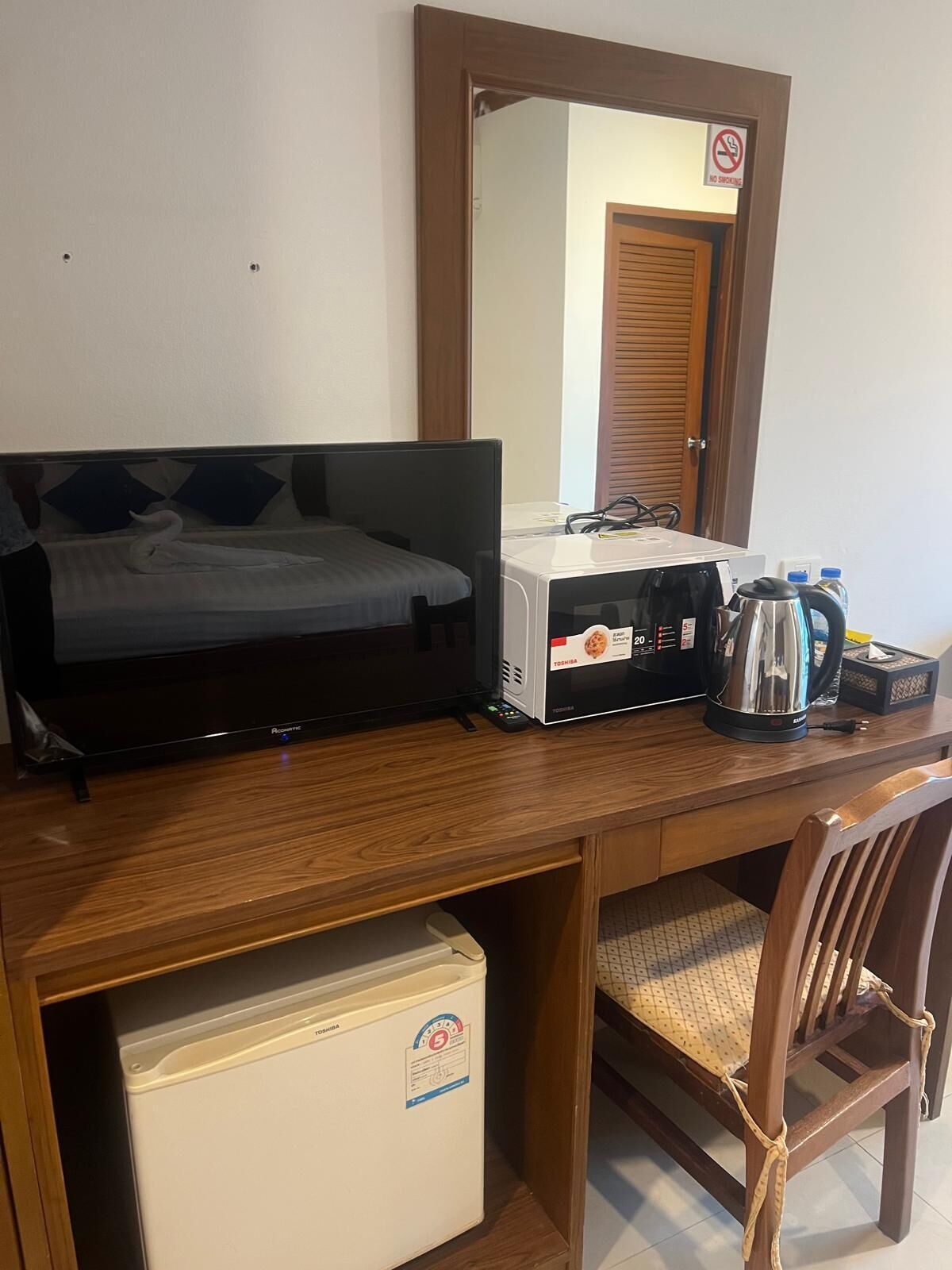 Une chambre d’hôtel équipée d’un lit, d’un bureau avec un ordinateur, d’une machine à café et d’un mini-réfrigérateur.