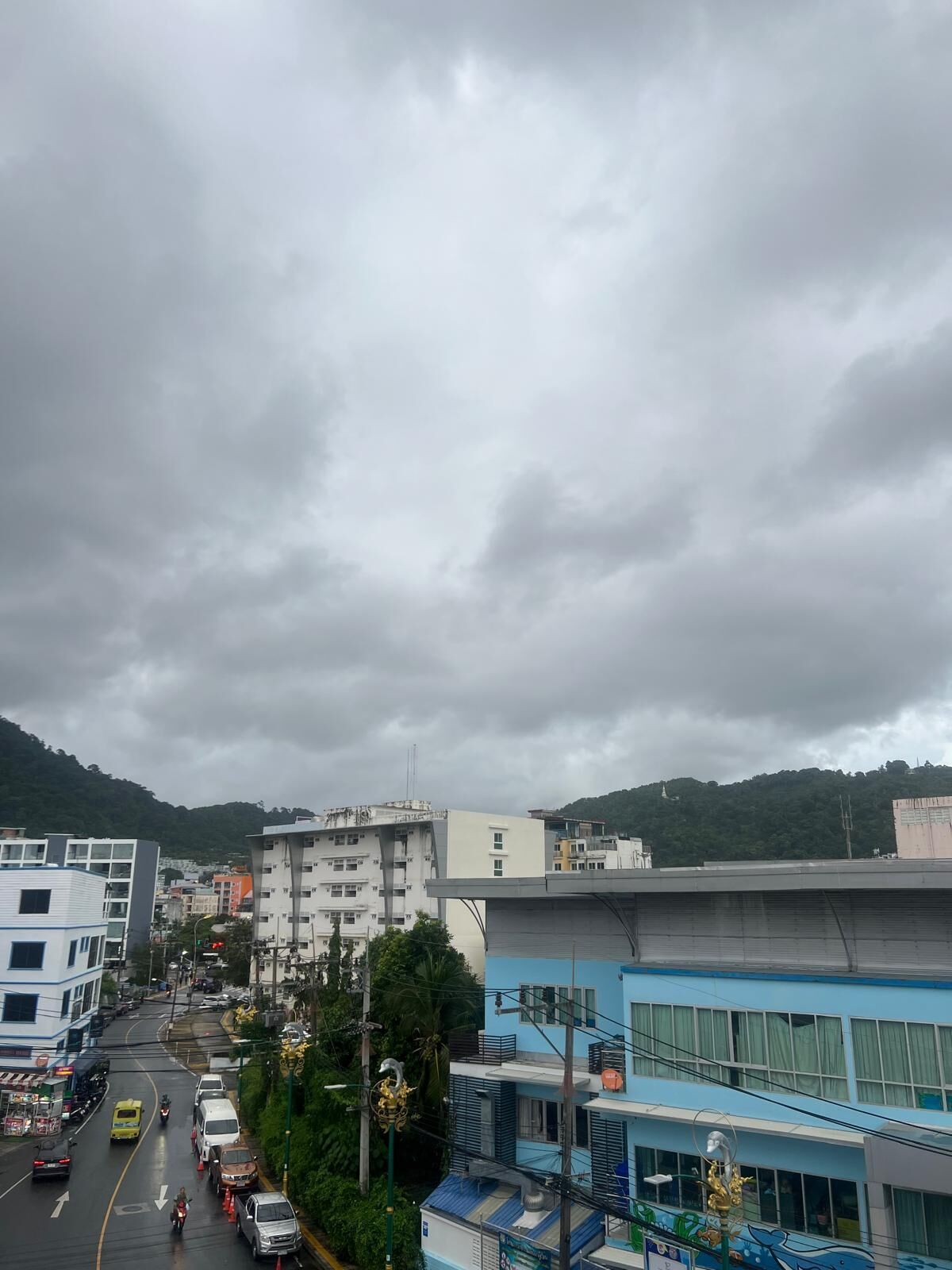 A city street with buildings, vehicles, and a mountainous backdrop.