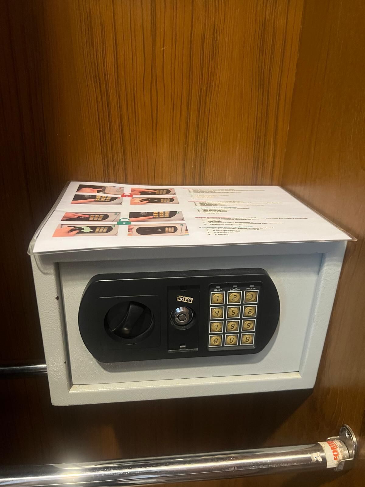 A safe with a keypad and a lock mechanism, accompanied by a manual with instructions.