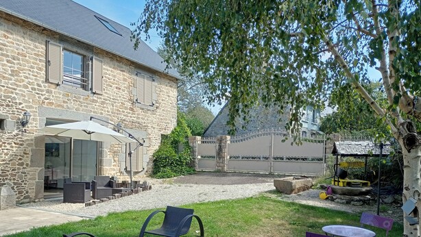 A stone building with a patio area, outdoor seating, and a small structure with a roof.