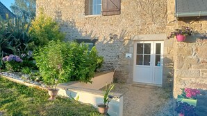 A stone house with a window, a door, and potted plants.
