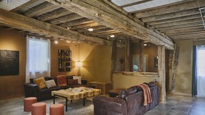 Un intérieur rustique avec des poutres apparentes, un canapé en cuir, une table basse et une cheminée.