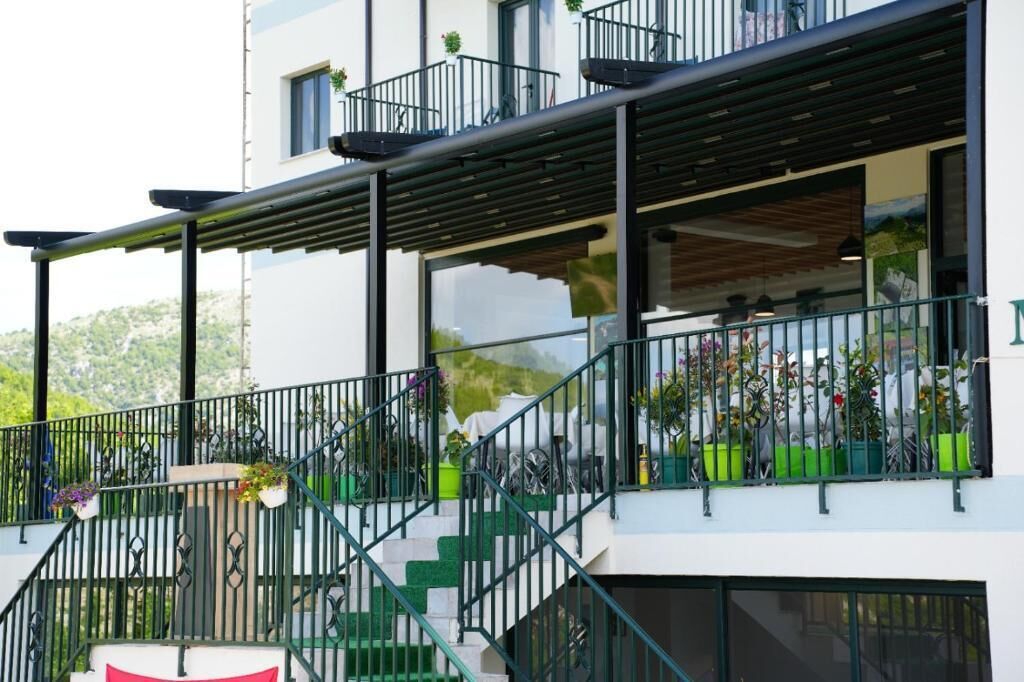 Een modern gebouw met balkon, terrasmeubilair en bloempotten.