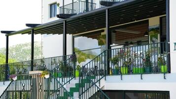 Een modern gebouw met balkon, terrasmeubilair en bloempotten.