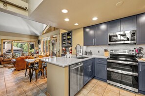 A modern kitchen with a central island, stainless steel appliances, and a dining area with a sofa and chairs.