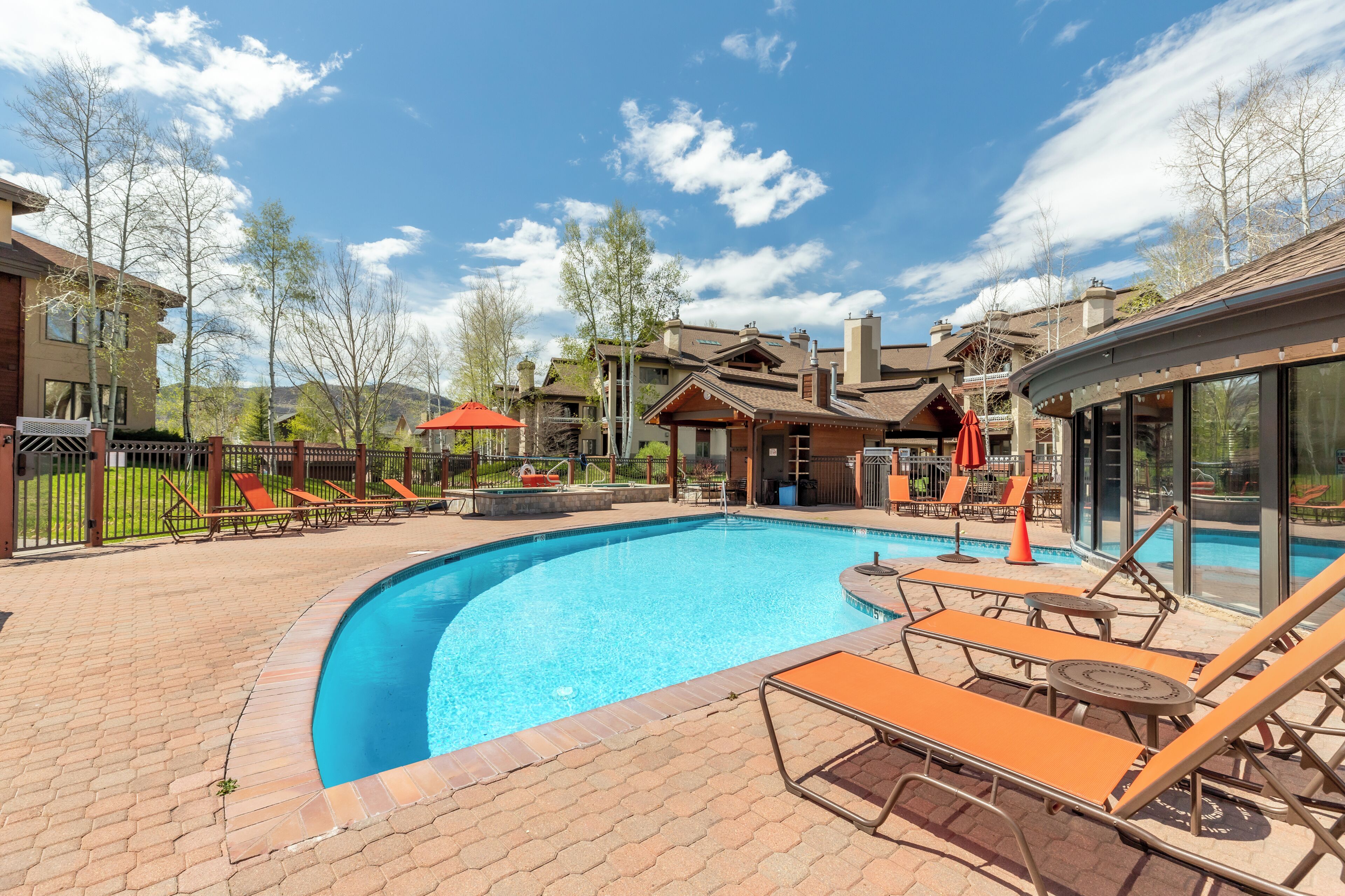 A swimming pool with lounge chairs and a brick patio.