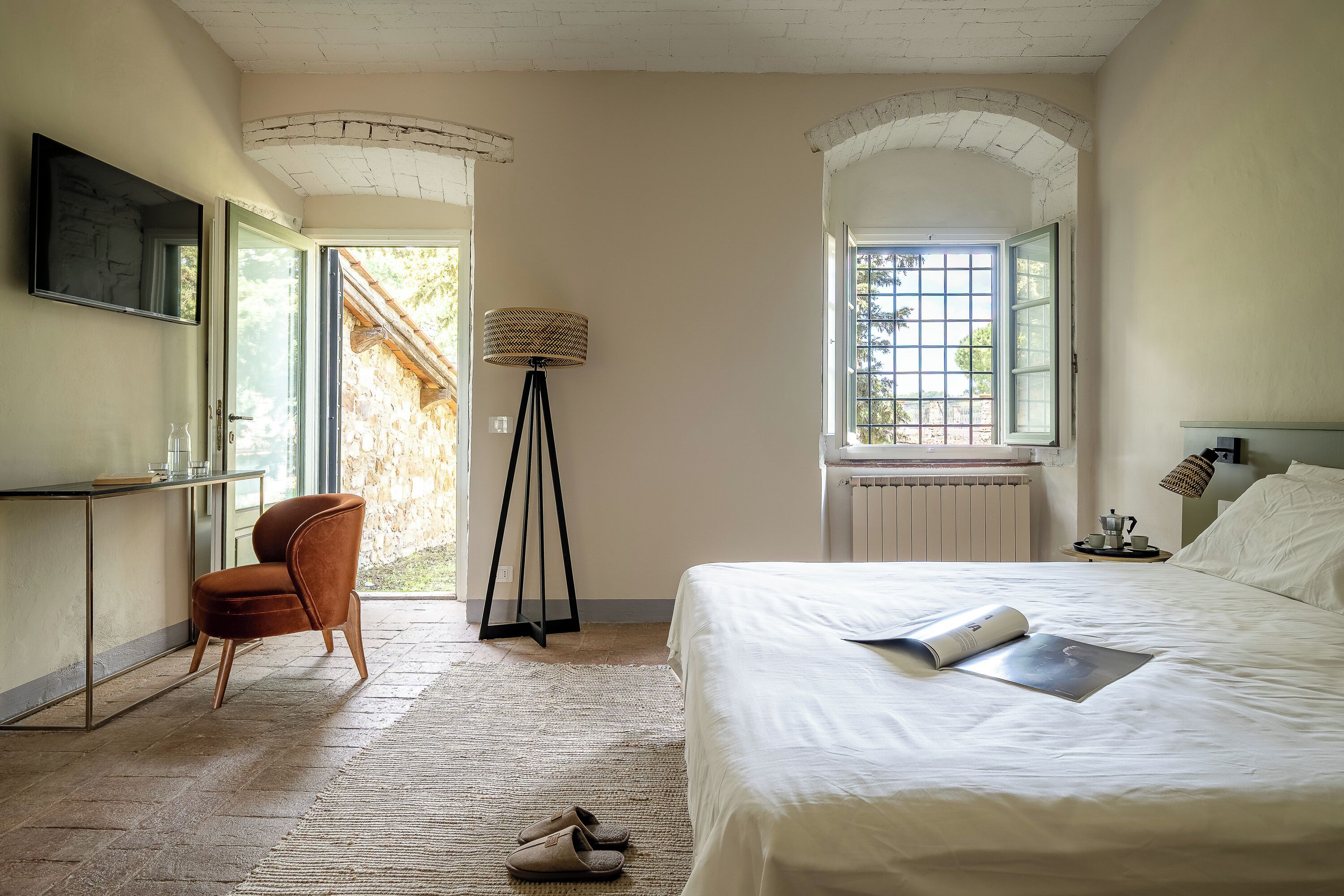 A bedroom with a bed, a chair, a desk, and a window.