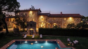 A stone building with a swimming pool and outdoor seating.