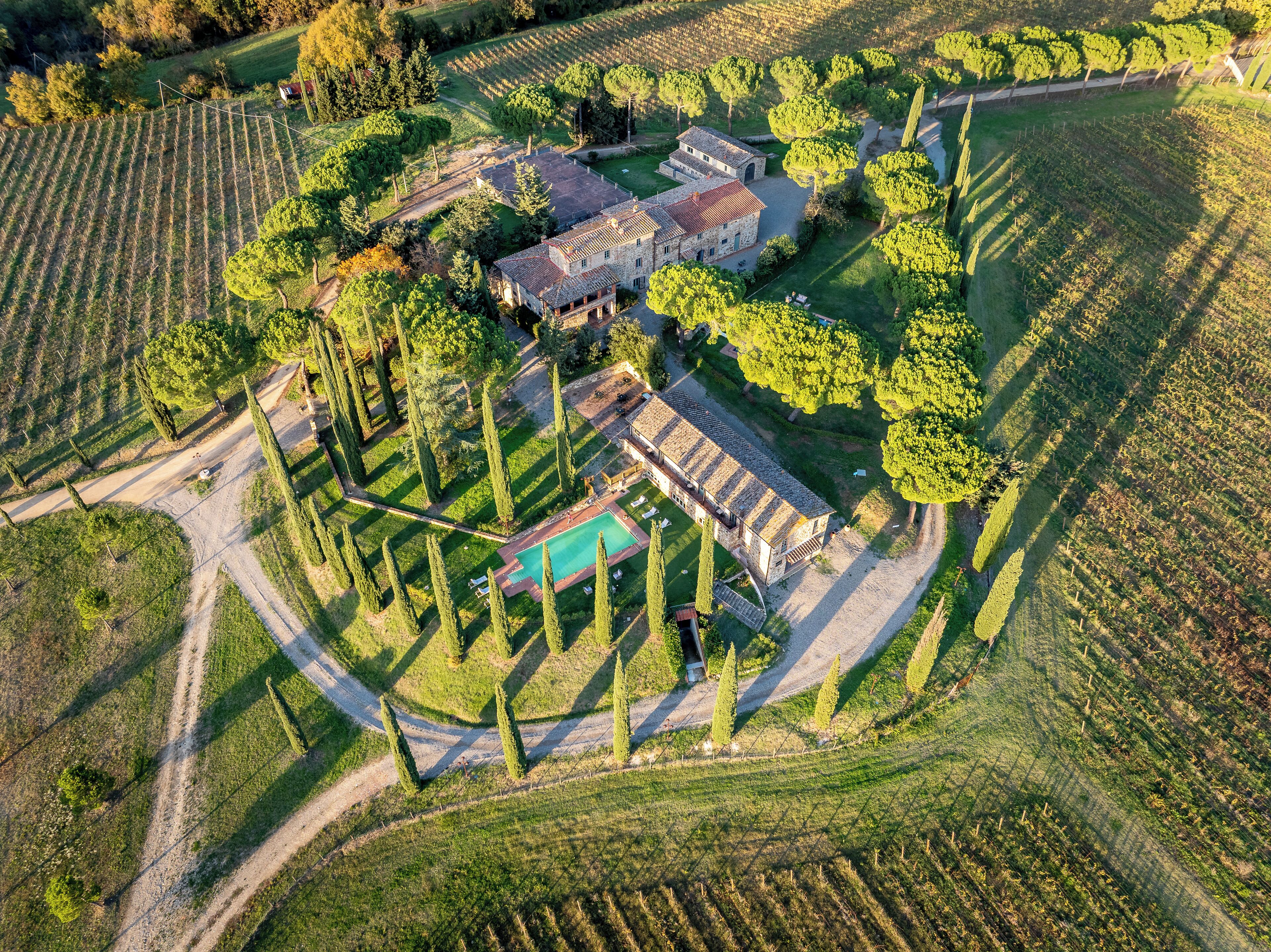 Vue aérienne d’une propriété dont le bâtiment principal est entouré de jardins aménagés et de vignobles.