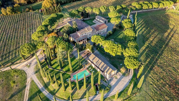 An aerial view of a property with a central building surrounded by landscaped gardens and vineyards.