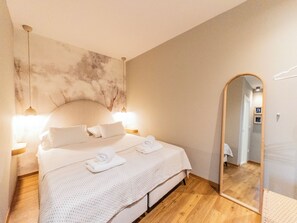 A bedroom with a large bed, two bedside lamps, a wall-mounted mirror, and a wooden floor. - Idonia Sea View Double Room  (Hvar)