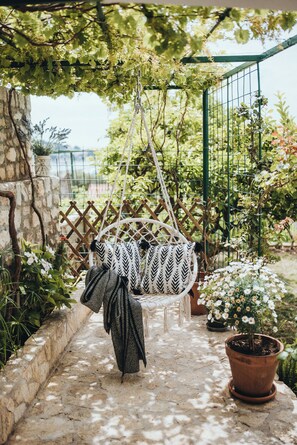 A garden with a hanging chair, a potted plant, and a stone wall. - Idonia Sea View Double Room  (Hvar)