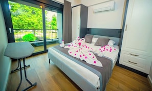 Una habitación de hotel moderna con una cama grande, una mesita y vistas a espacios verdes.