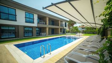 Una piscina al aire libre de temporada, sombrillas, tumbonas