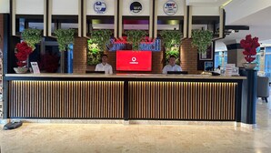 A hotel reception desk with a red logo, multiple certifications, and a modern design. - Sweet Home Kemer Apartments (Kemer)