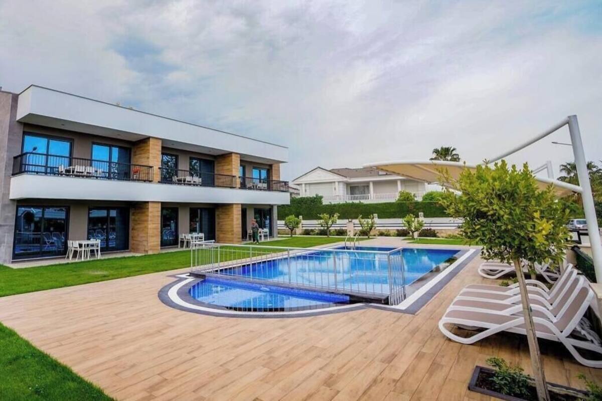 A modern two-story house with a swimming pool, outdoor seating, and a well-maintained lawn.