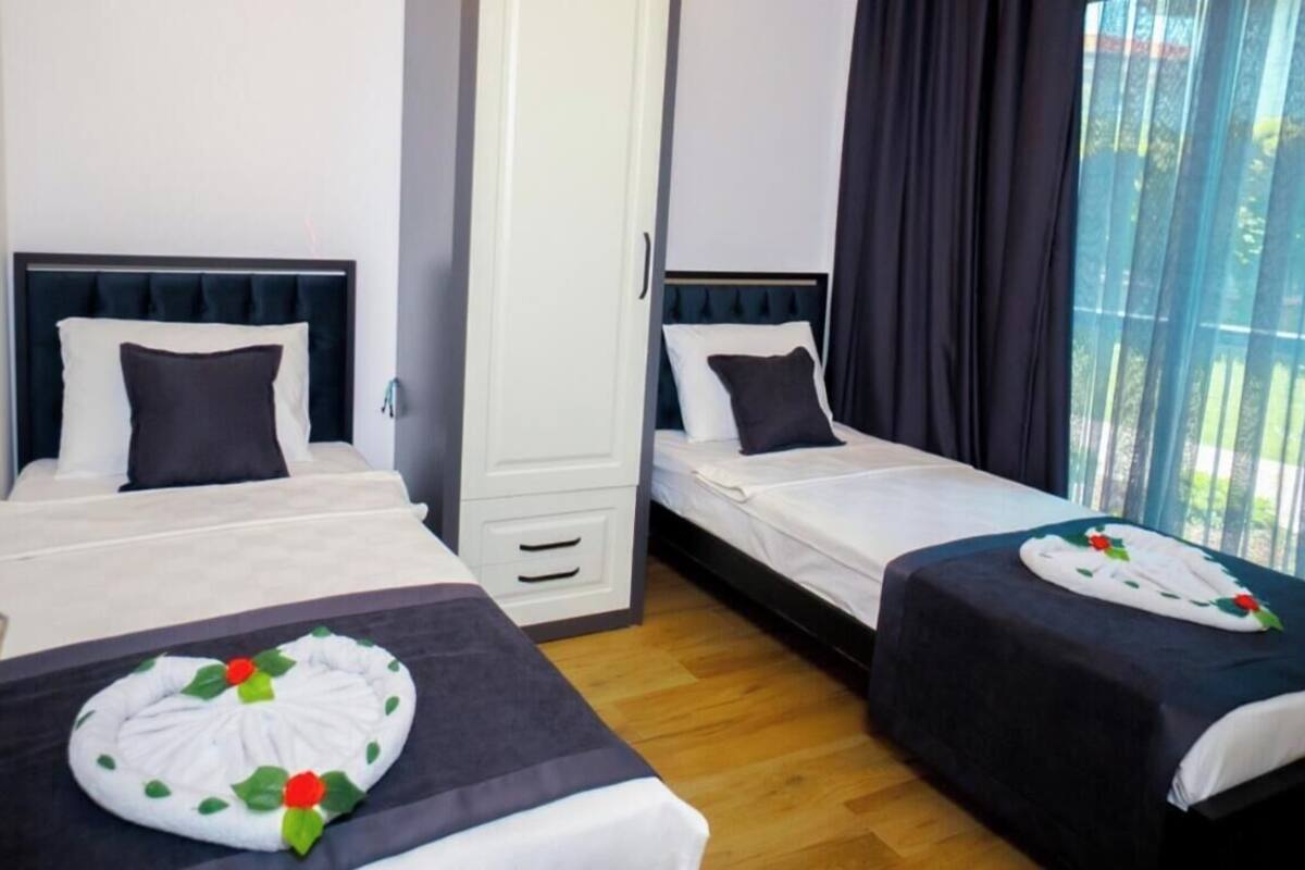 A hotel room with two beds, a wardrobe, and a view through large windows.
