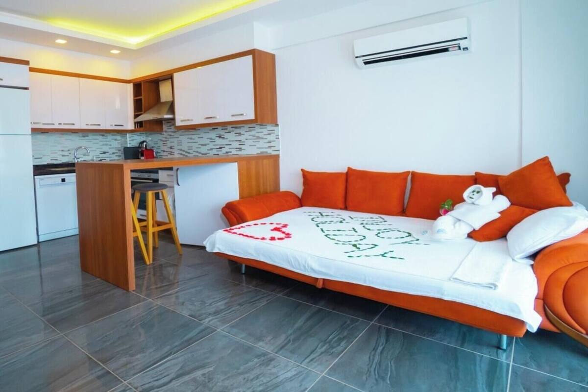 A compact hotel room with a bed, a desk, a kitchenette, and a bathroom.