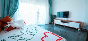 Ein Hotelzimmer mit Bett, Fernseher, einem Holzschrank und einem Fenster mit Vorhängen.